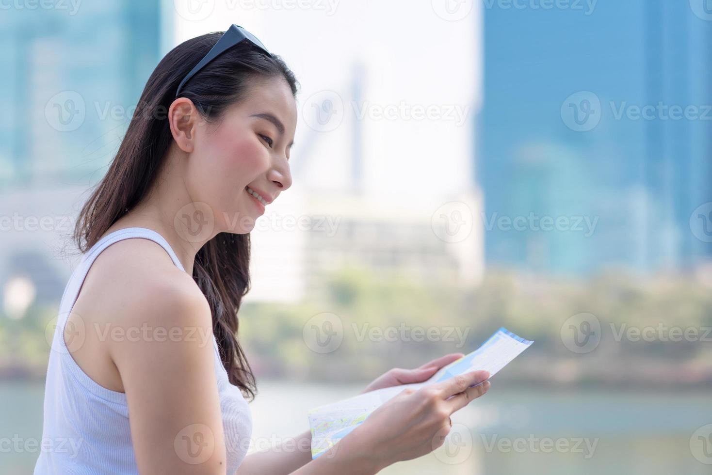 bella donna turistica asiatica che guarda la mappa per cercare la posizione del punto di riferimento. viaggio di vacanza in estate foto