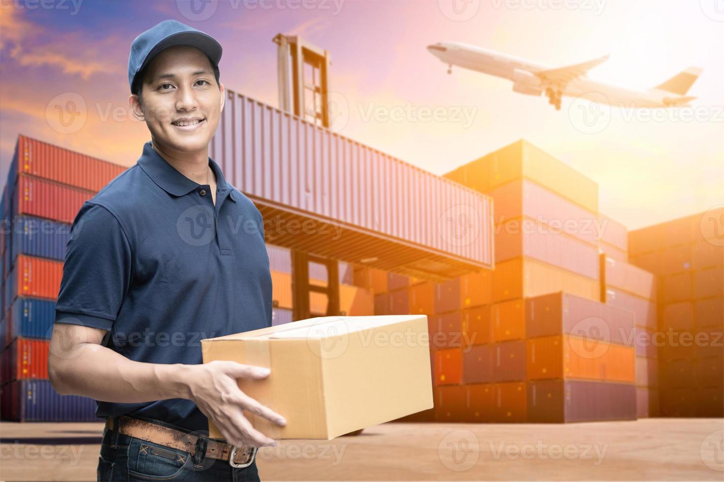 fattorino asiatico che tiene una scatola di cartone con sfondo di cantiere logistico per il concetto di e-commerce e logistica. foto