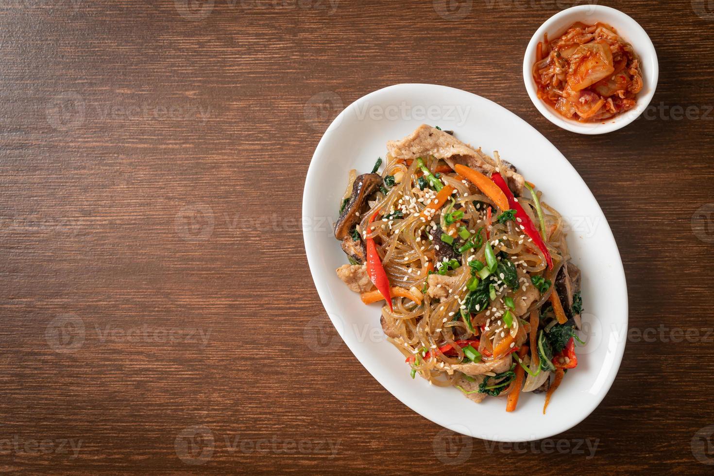 japchae o vermicelli coreani saltati in padella con verdure e maiale conditi con sesamo bianco foto