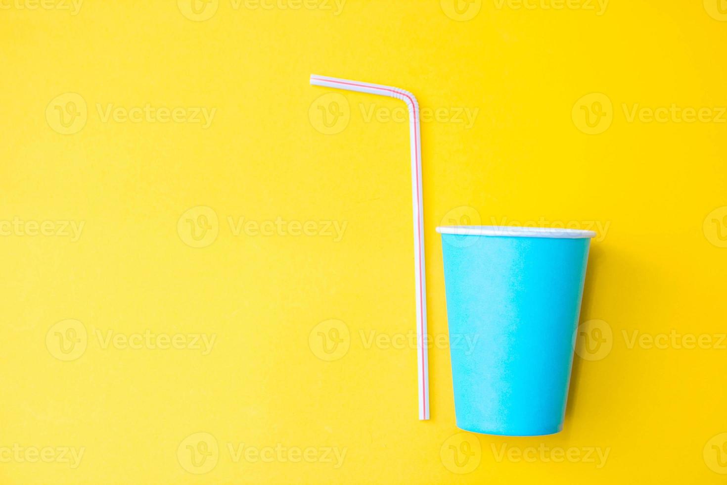 bicchieri di carta blu con cannucce di plastica colorate su sfondo giallo. impostato per la festa. vista dall'alto. stile minimalista. copia, spazio vuoto per il testo foto
