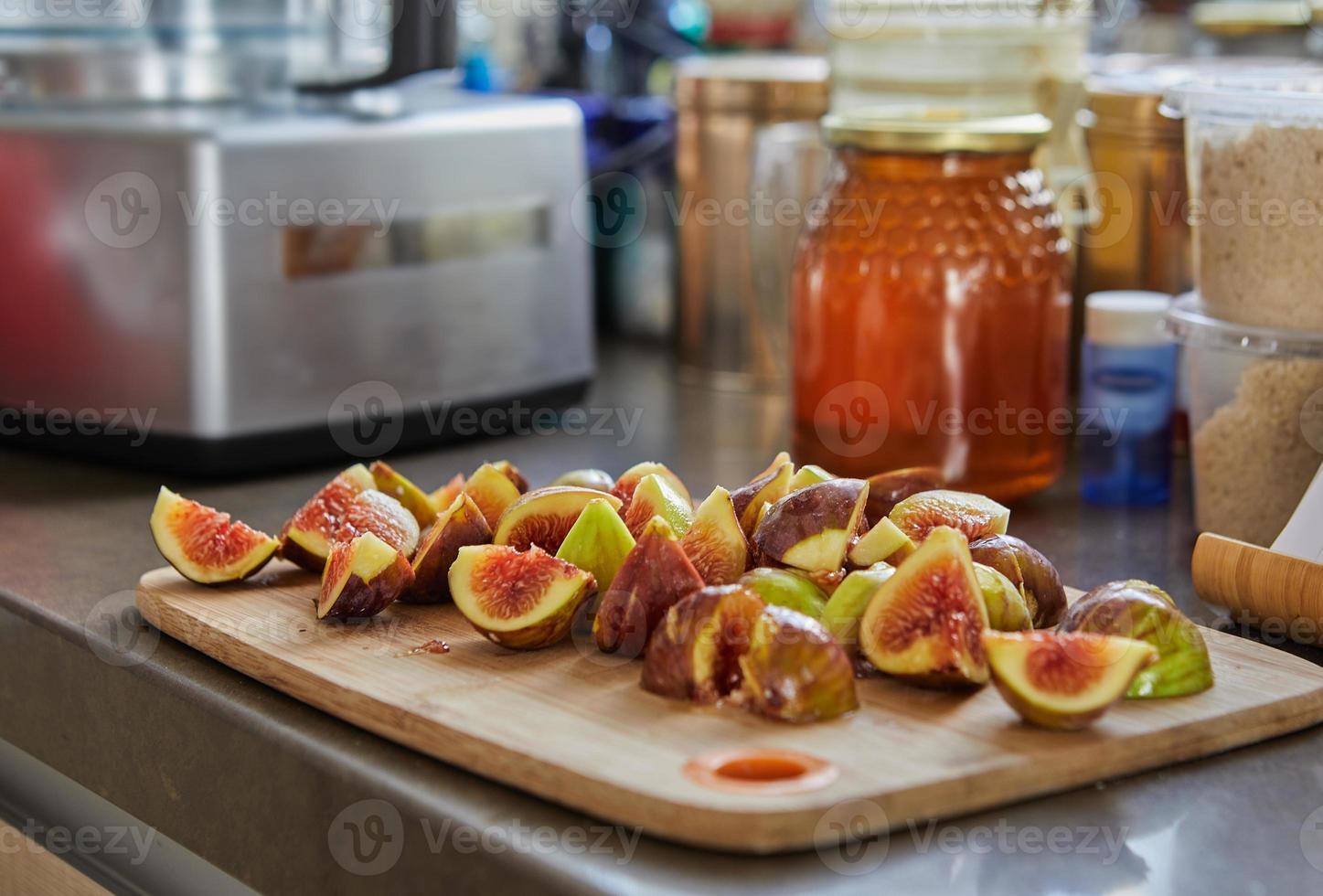 i fichi giacciono su una tavola di legno in cucina e un barattolo di miele per cuocere la ricetta da internet foto