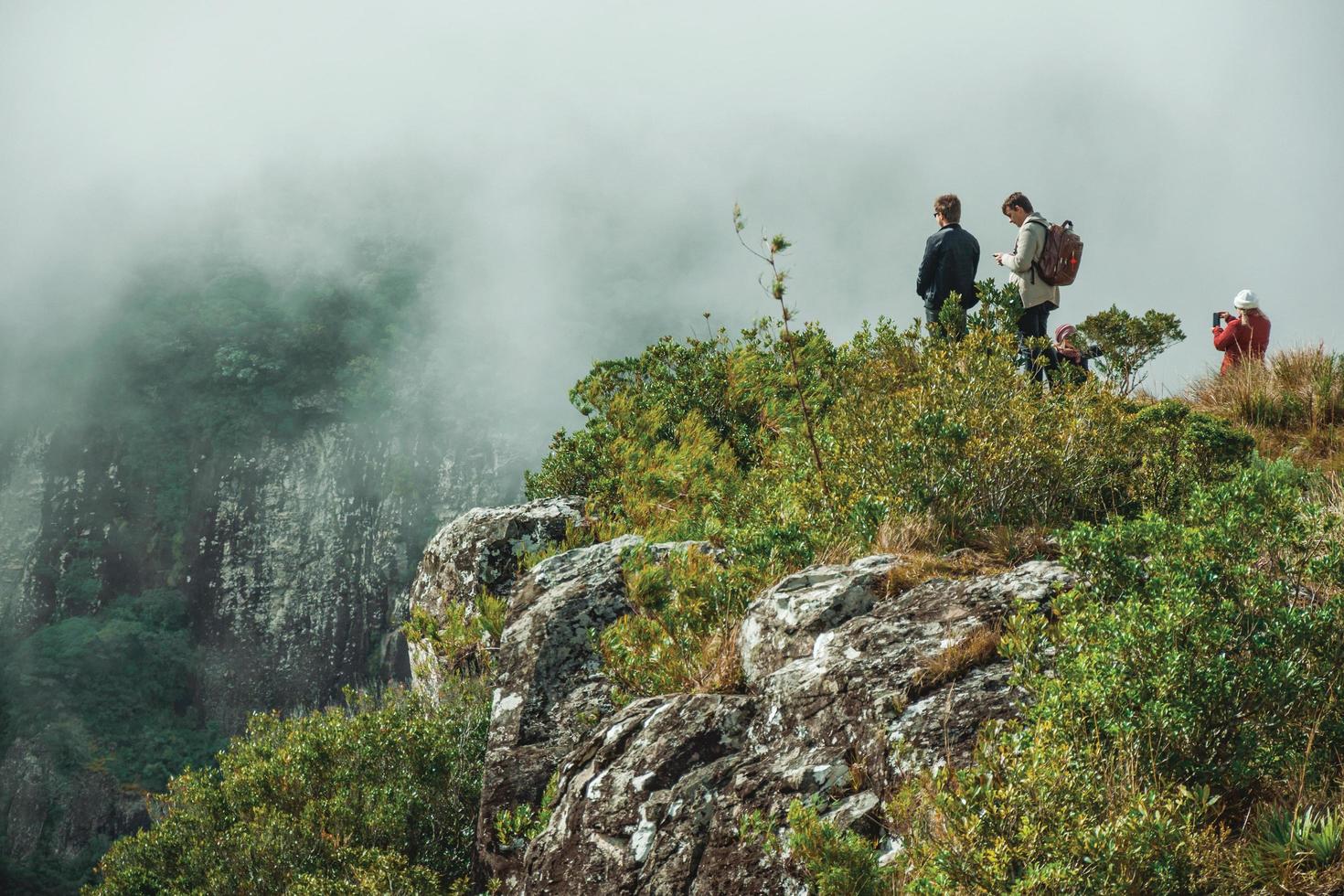 cambara do sul, brasile - 18 luglio 2019. persone su ripida scogliera rocciosa a fortaleza canyon con nebbia che sale il burrone vicino a cambara do sul. un piccolo paese rurale con incredibili attrazioni turistiche naturali. foto