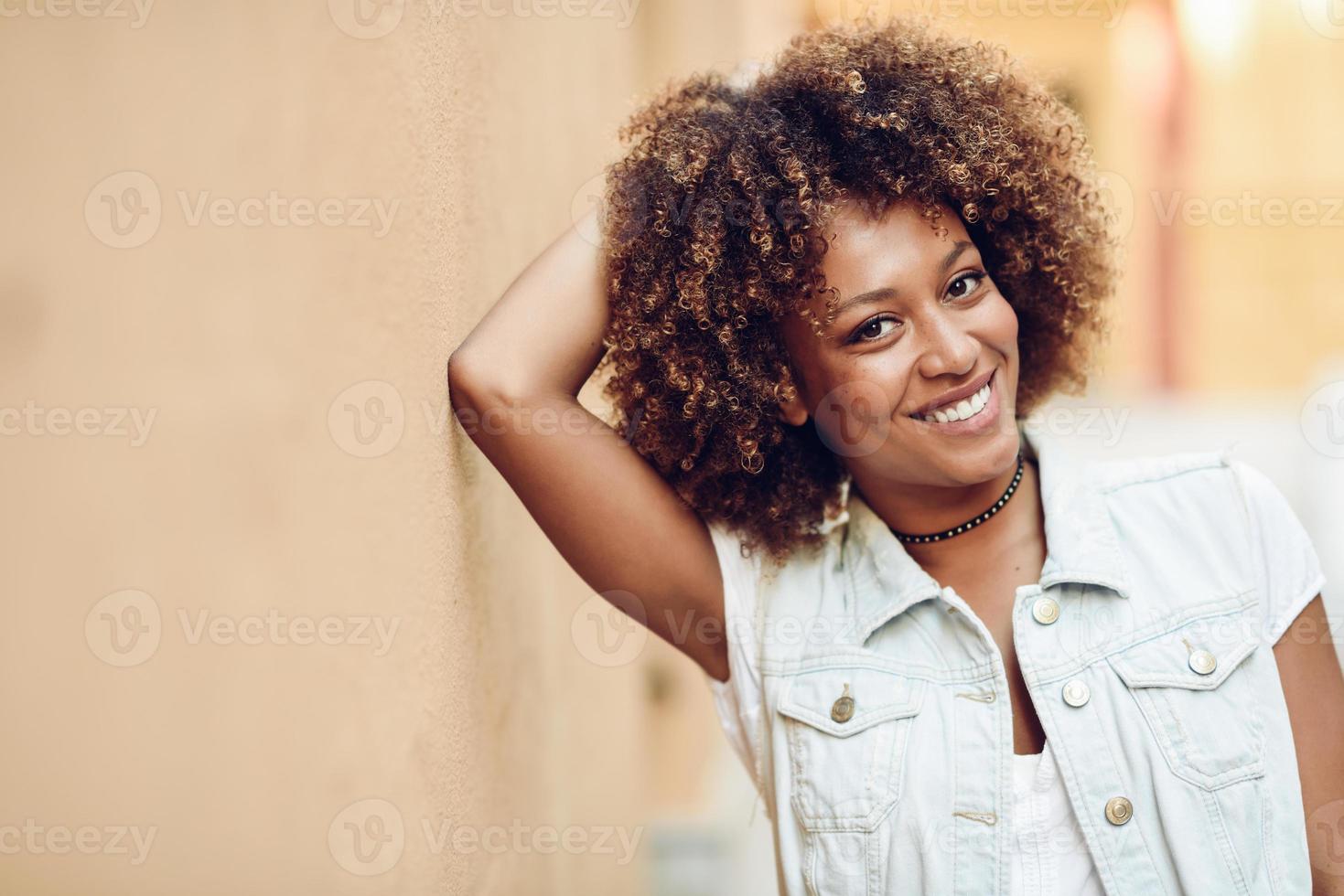 giovane donna di colore, acconciatura afro, sorridente in background urbano foto