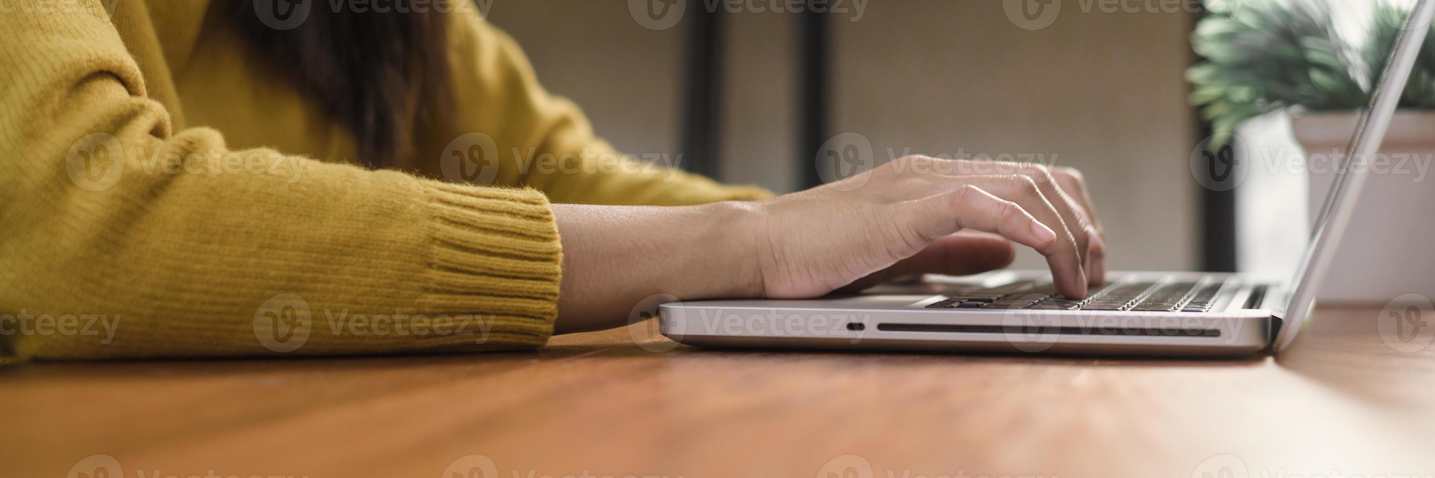 giovane donna che lavora con il computer portatile su una scrivania in una caffetteria. giovane donna che lavora nel fine settimana con il suo computer portatile in una calda giornata di sole. laptop che lavora nel concetto di caffetteria. striscione panoramico. foto