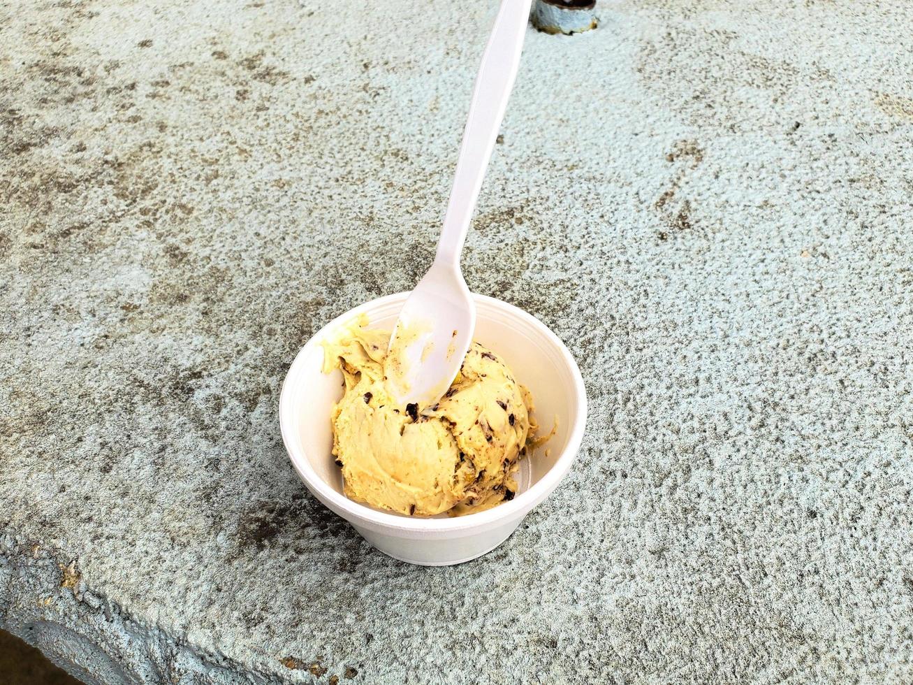 gelato al gusto di cioccolato bianco dessert congelato modello in cono di cialda che tiene la mano sul tavolo. foto