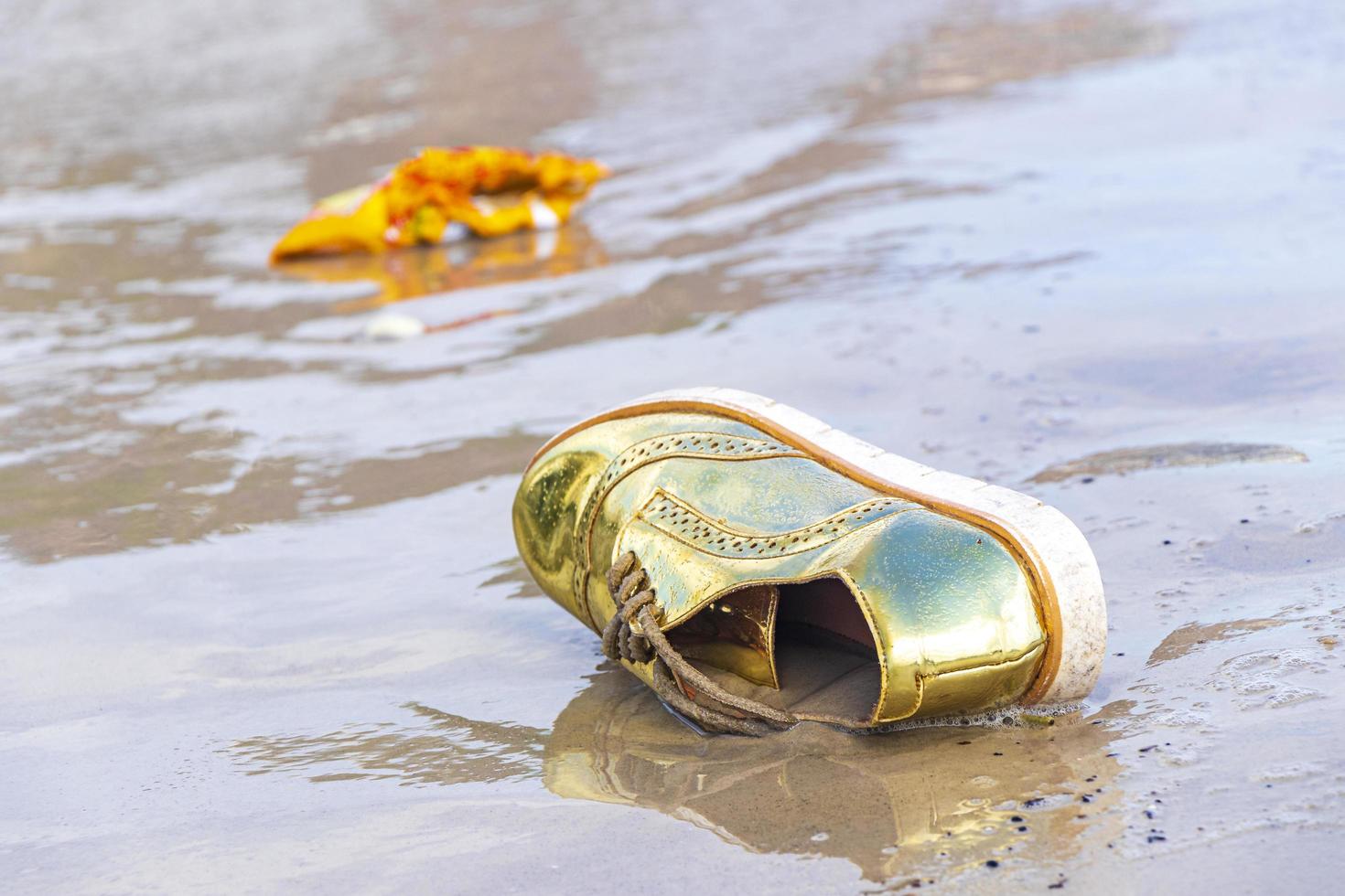 Scarpa d'oro arenata l'inquinamento dei rifiuti lavato sulla spiaggia brasile. foto