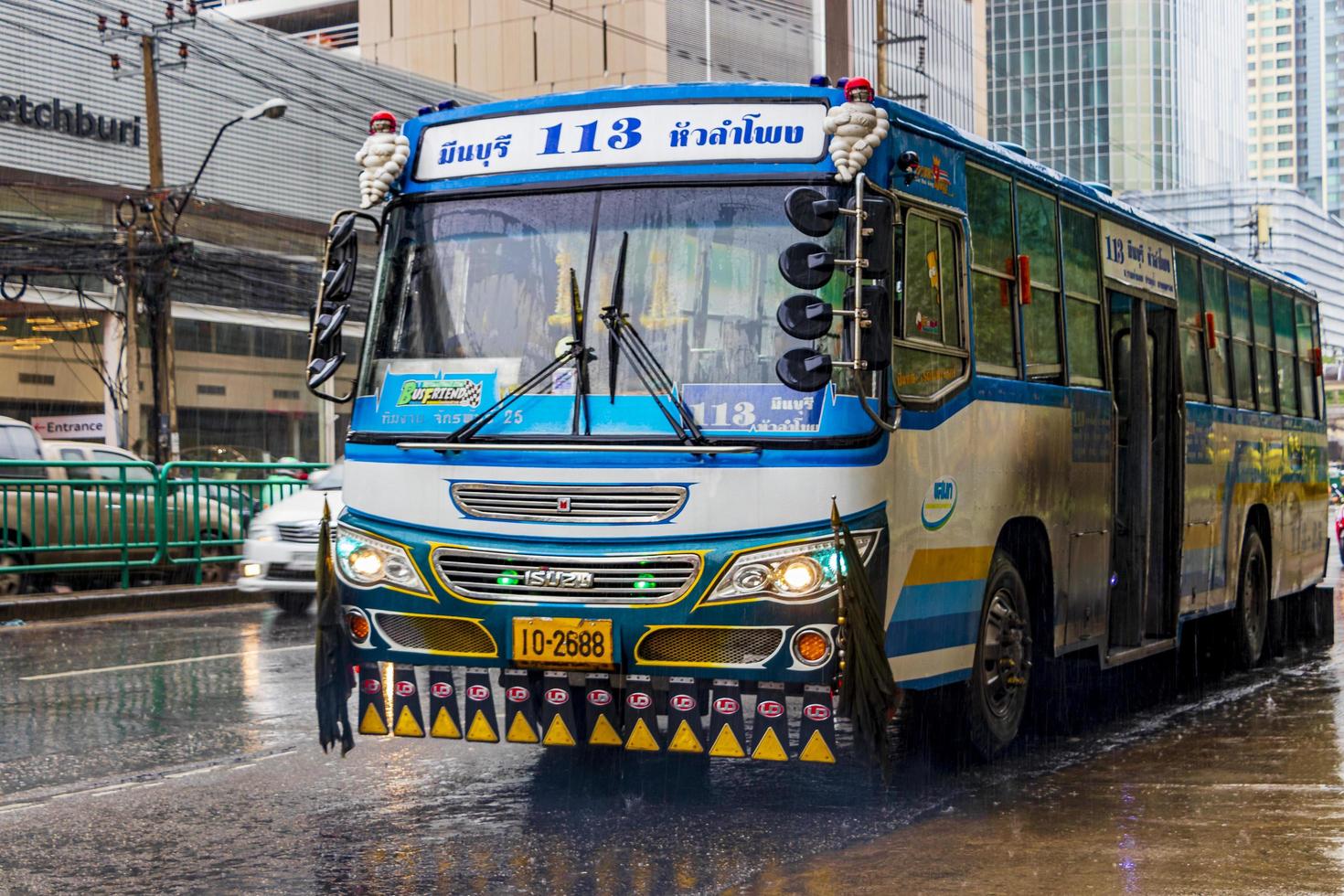 tipico autobus decorato blu colorato sotto la pioggia battente bangkok thailandia. foto