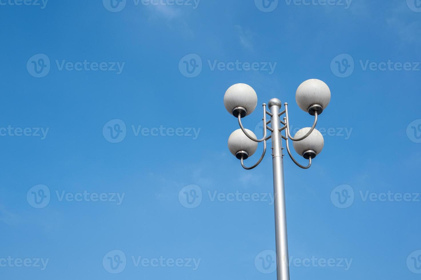 un lampione composto da quattro lampadine rotonde sotto il cielo azzurro foto