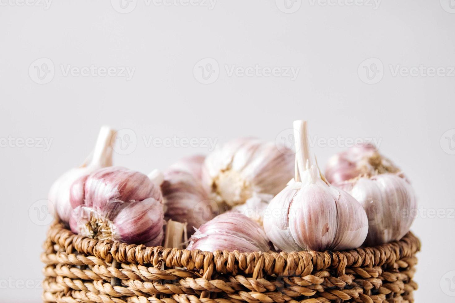 aglio in un cesto di vimini su sfondo bianco foto