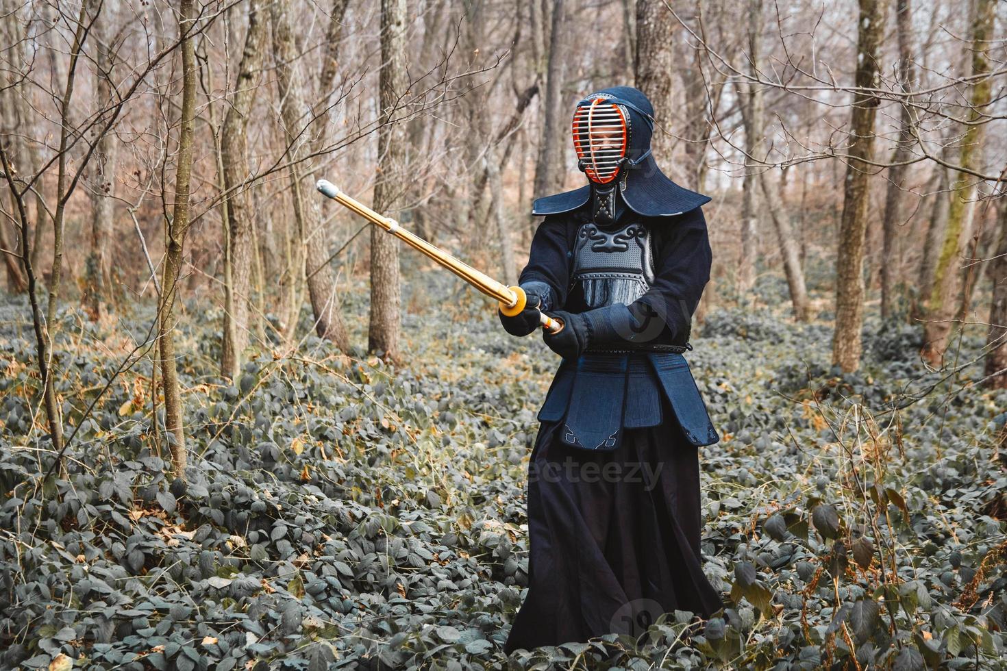 uomo che pratica kendo con spada di bambù shinai sullo sfondo della foresta foto