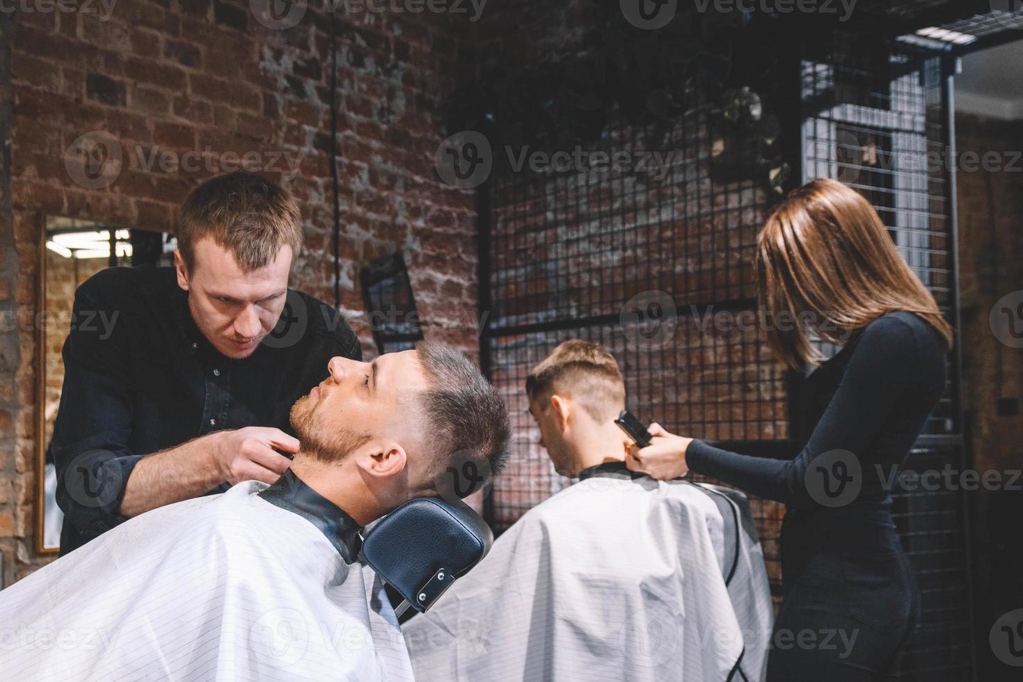 i parrucchieri tagliano i loro clienti dal barbiere. pubblicità e concetto di negozio di barbiere foto