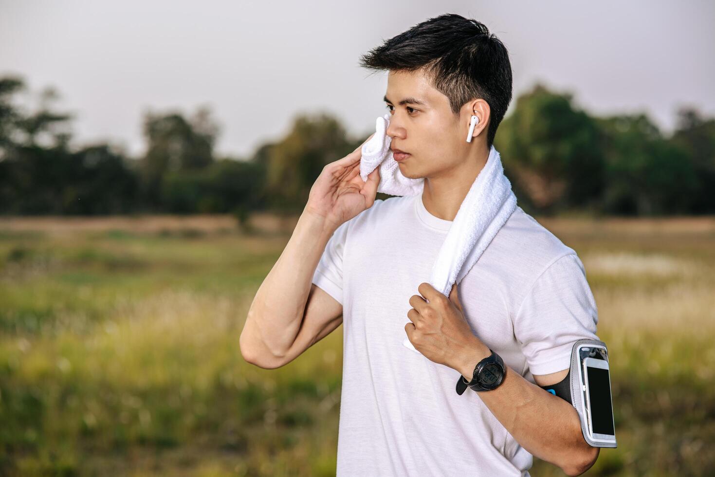 un uomo in camicia bianca si alzò e si tenne un fazzoletto sul collo per asciugarsi il viso. foto