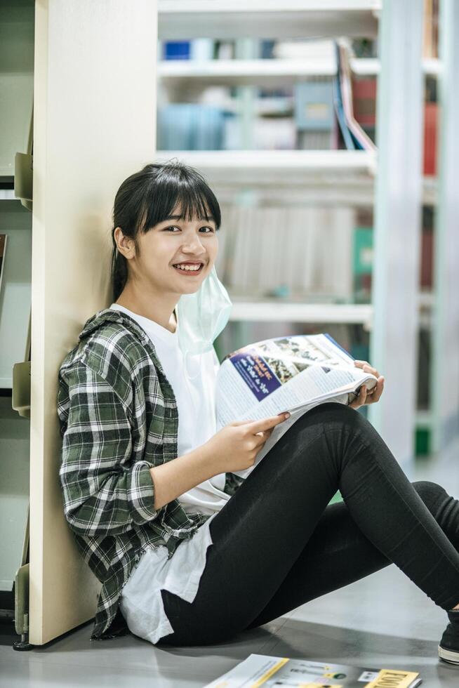 una donna seduta a leggere un libro in biblioteca. foto