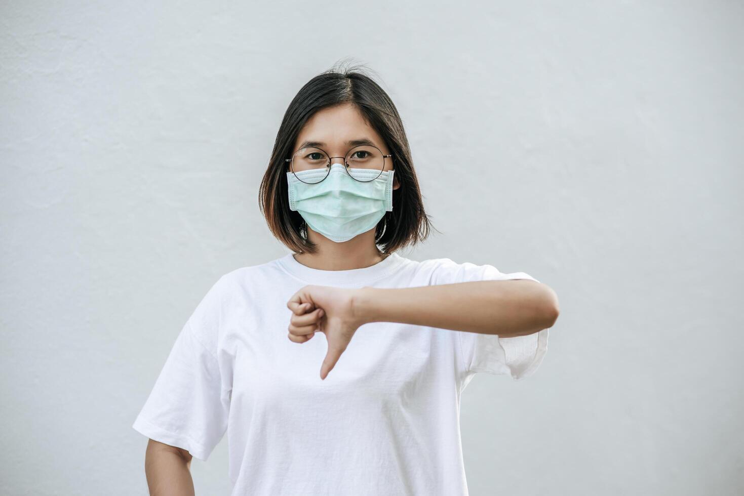 la donna indossa una maschera e punta il pollice verso il basso. foto