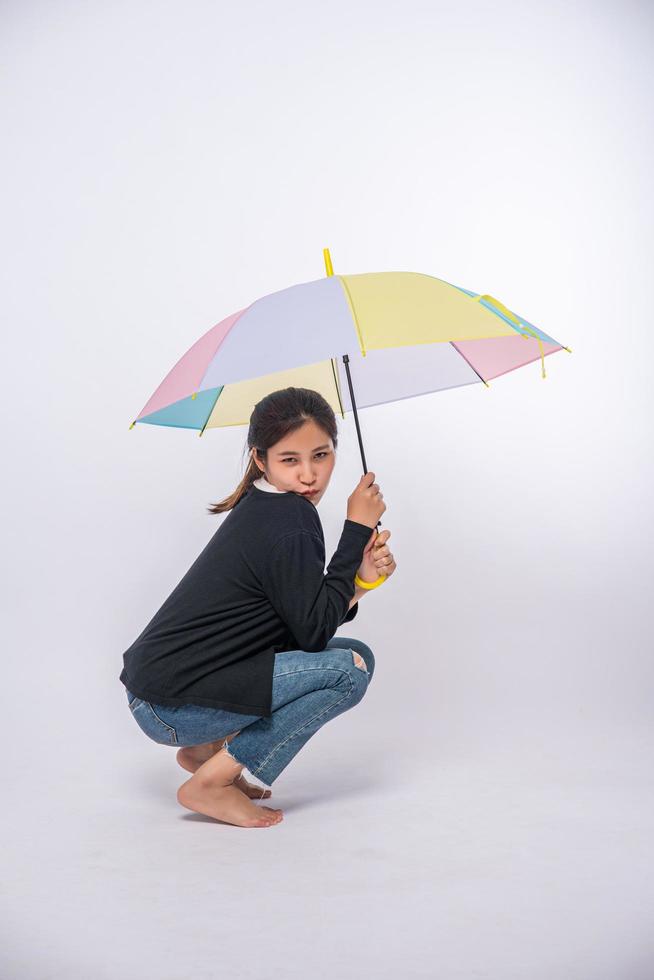 donna in camicia nera seduta e allargando un ombrello foto