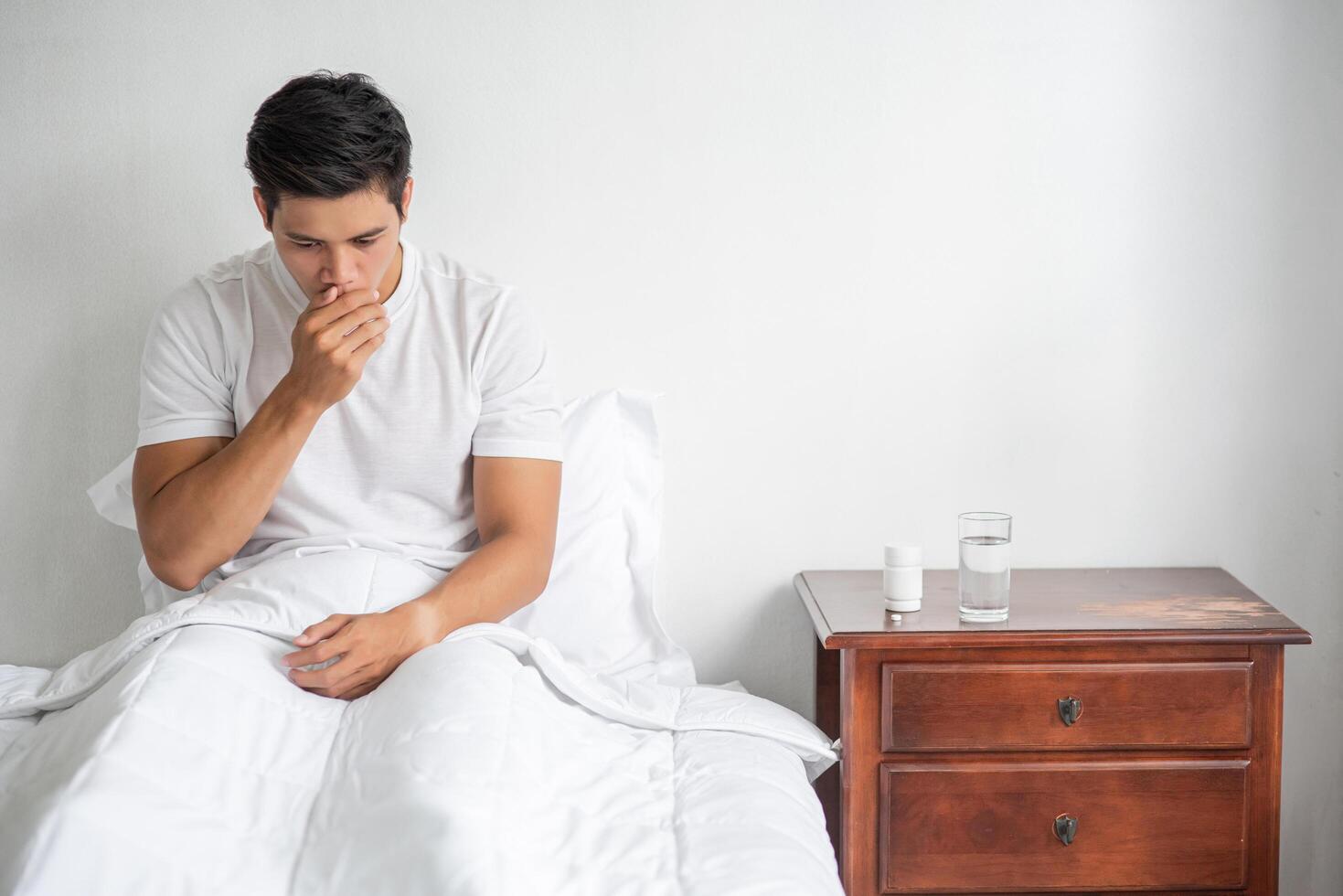 l'uomo tossì, si portò una mano alla bocca e si sedette sul letto. foto