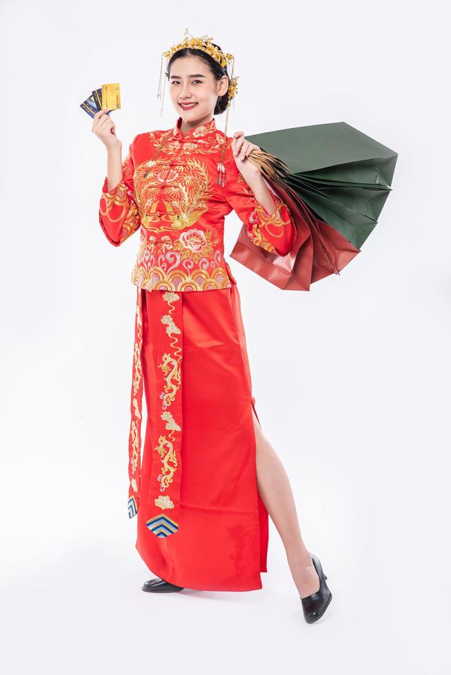 la donna indossa un abito cheongsam sorride con un sacchetto di carta dallo shopping nel capodanno cinese foto