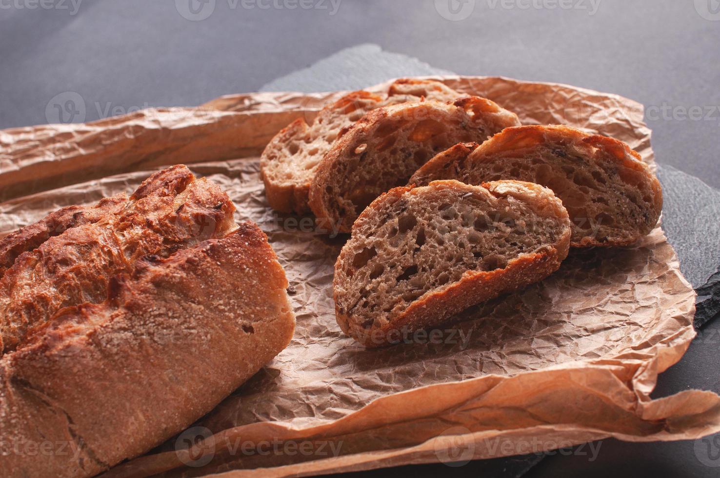 pane a fette adagiato su tavola nera da servire su carta forno. foto