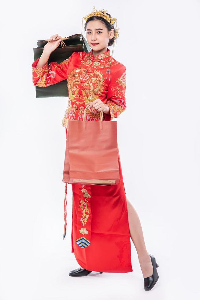 la donna indossa un abito cheongsam sorride con un sacchetto di carta dallo shopping nel capodanno cinese foto