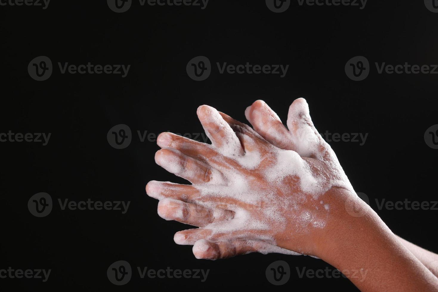 giovane che si lava le mani con acqua calda e sapone foto