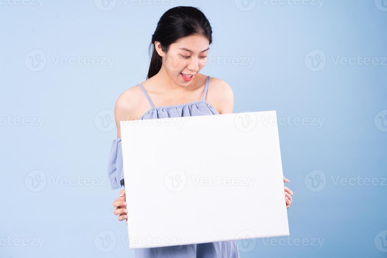 immagine di una ragazza asiatica che tiene una lavagna bianca, isolata su sfondo blu foto