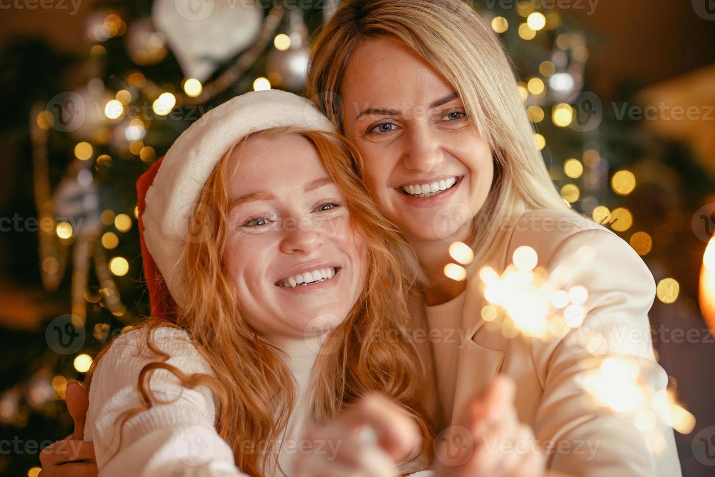 coppia lesbica a cena per celebrare una vacanza. le ragazze bruciano stelle filanti e sorridono alla telecamera foto