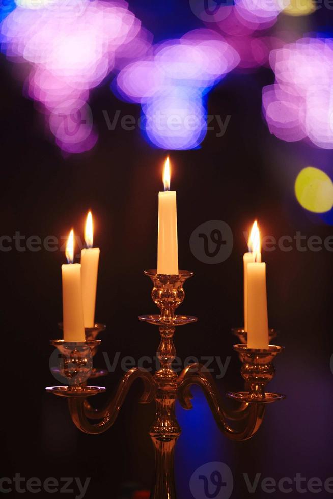 candele accese sul candeliere in bronzo su sfondo scuro a casa.candele all'interno. stile vintage. calma atmosfera romantica. immagine orizzontale per il design. foto