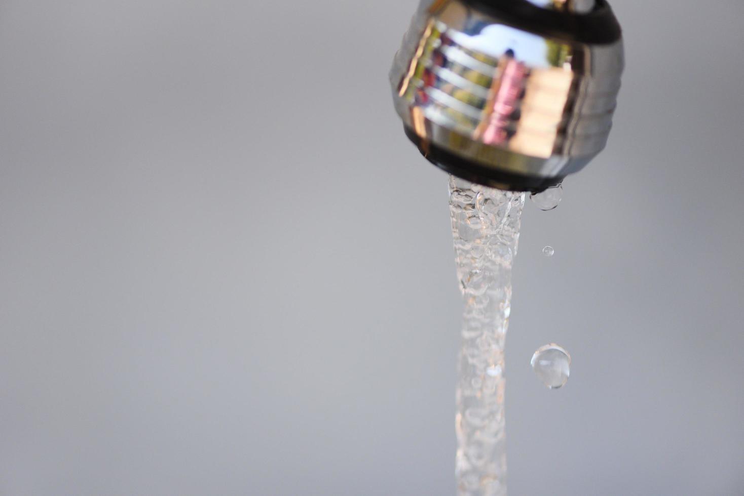acqua del rubinetto goccia d'acqua dal rubinetto su sfondo grigio foto