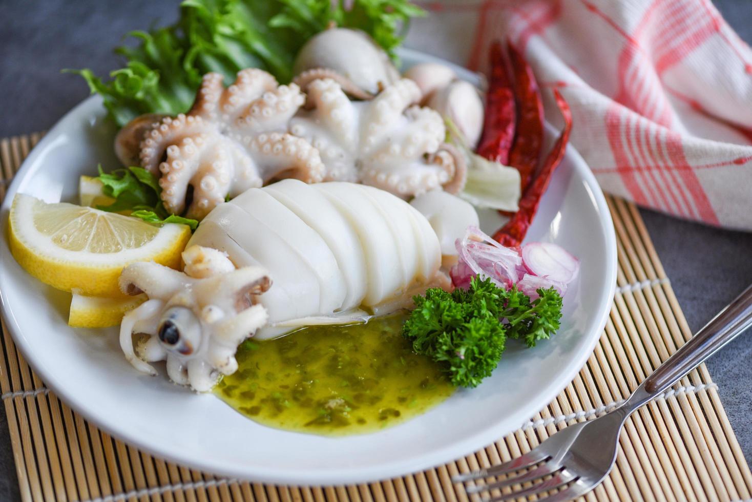 Insalata di calamari spezie limone aglio salsa chili servita su piastra bianca sfondo - cibo cotto calamari polpo o seppie al ristorante di pesce foto