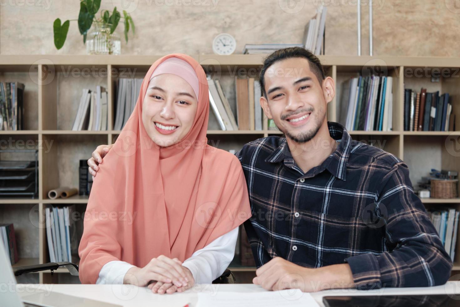 ritratto di imprenditori startup persone, giovane maschio e bella proprietaria, due partner che coppia islamica, guardando la fotocamera, sorride felicemente nel piccolo ufficio sul posto di lavoro di e-commerce. foto