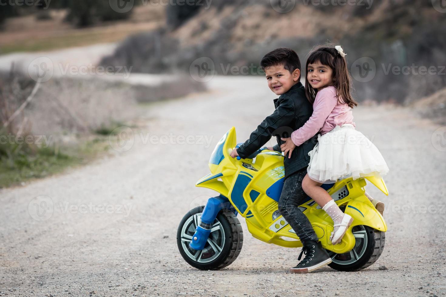 ragazzino e ragazza in sella a una moto giocattolo foto