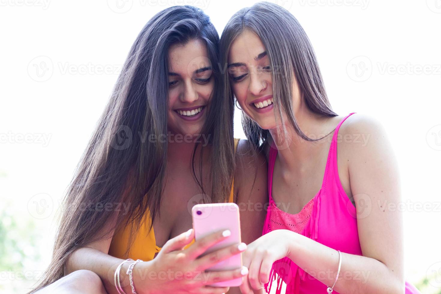 due ragazze in costume da bagno che usano i cellulari e si divertono in piscina. avvicinamento foto