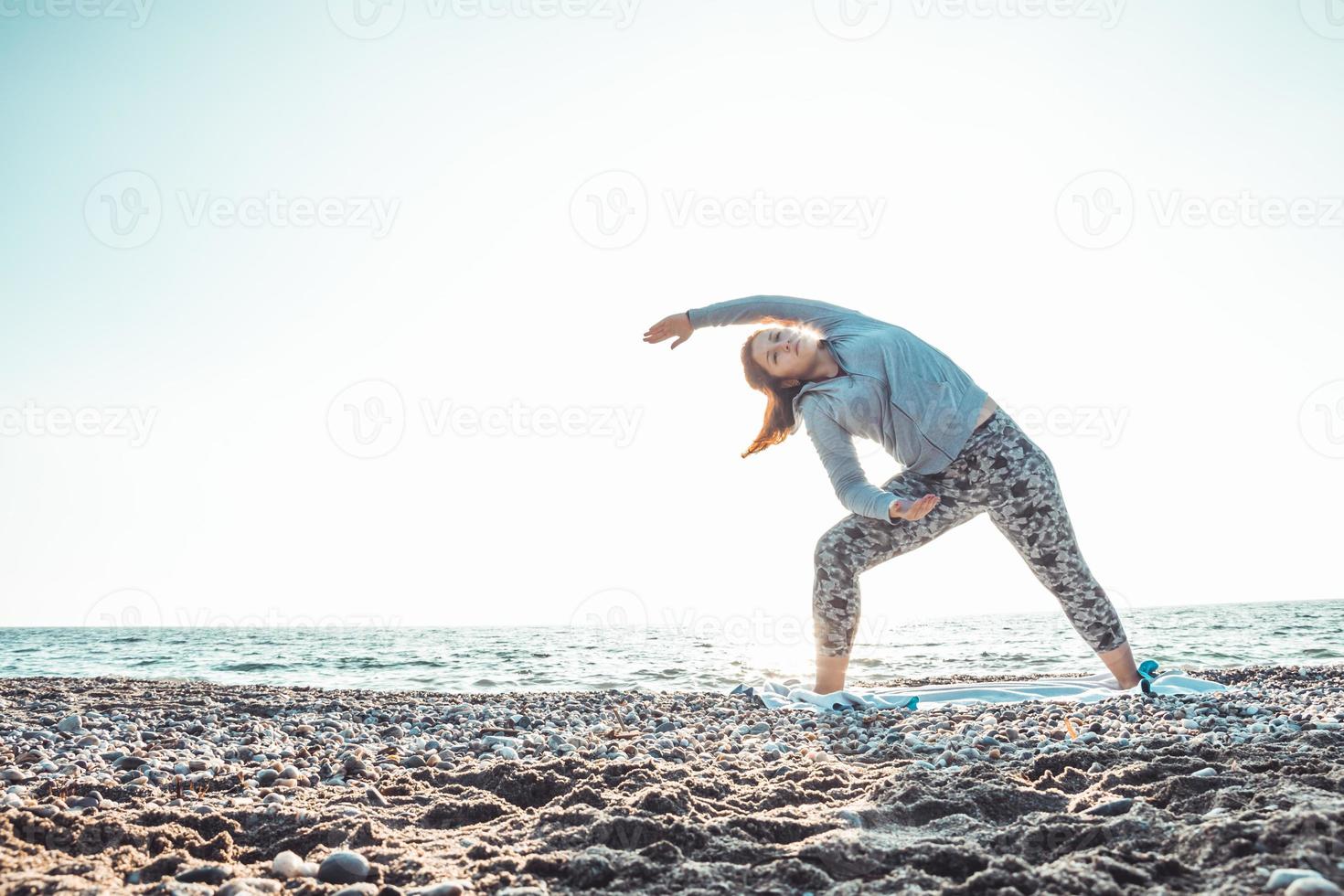 ragazza che fa yoga e si allunga sulla spiaggia con il suo cane foto