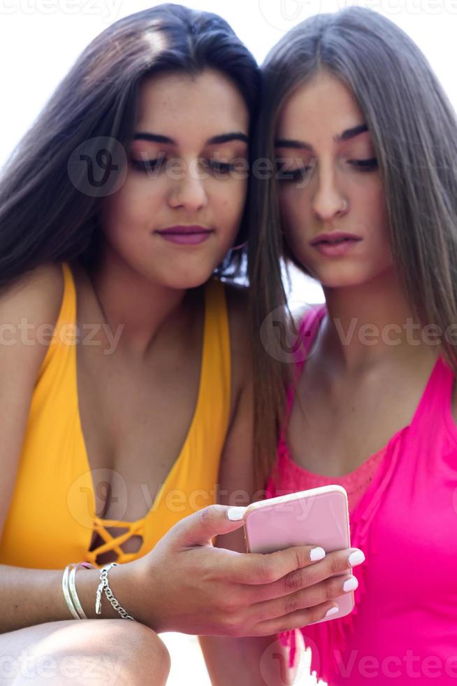 due ragazze in costume da bagno che usano i cellulari e si annoiano in piscina. avvicinamento foto