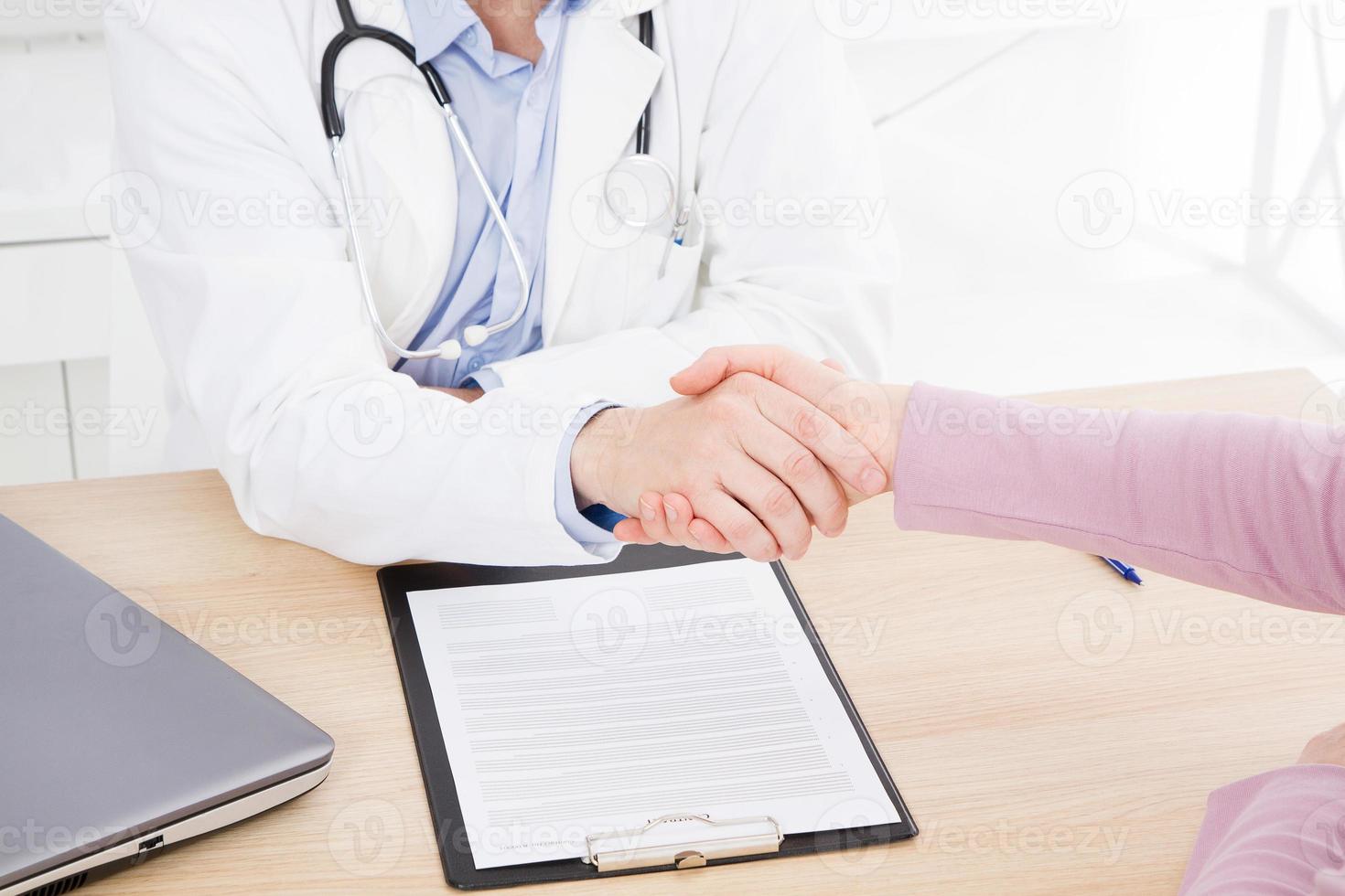 la mano maschile del medico scuote il braccio femminile del suo paziente in clinica, studio medico. concetto di assistenza sanitaria, assicurazione sanitaria foto