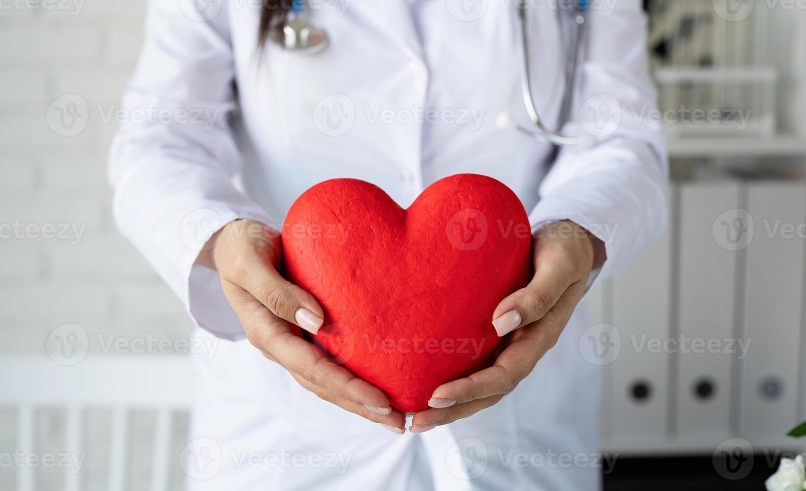 medico o scienziato donna che tiene in mano un grande cuore rosso foto