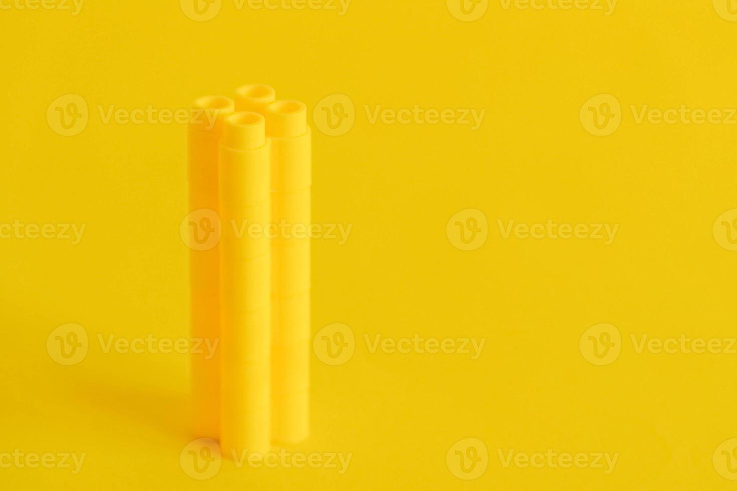blocchi di plastica gialli a forma di torre su sfondo giallo. sfondo di dettagli in plastica blocchi da costruzione foto