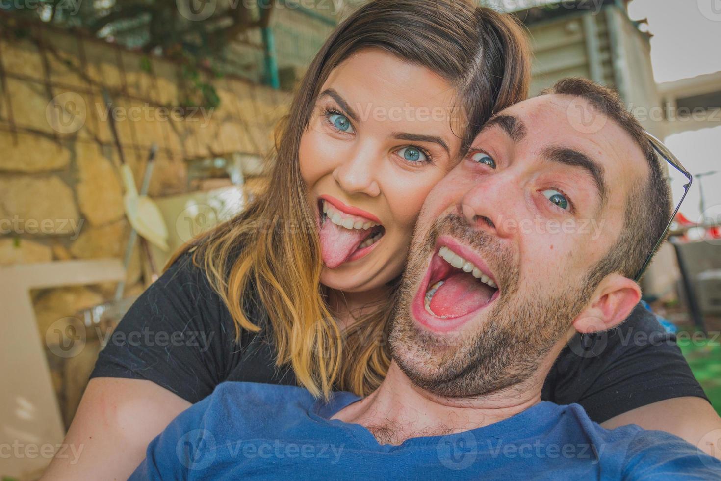 giovane coppia godendo insieme nel cortile di casa. stanno sorridendo, ridendo e facendo facce buffe insieme foto