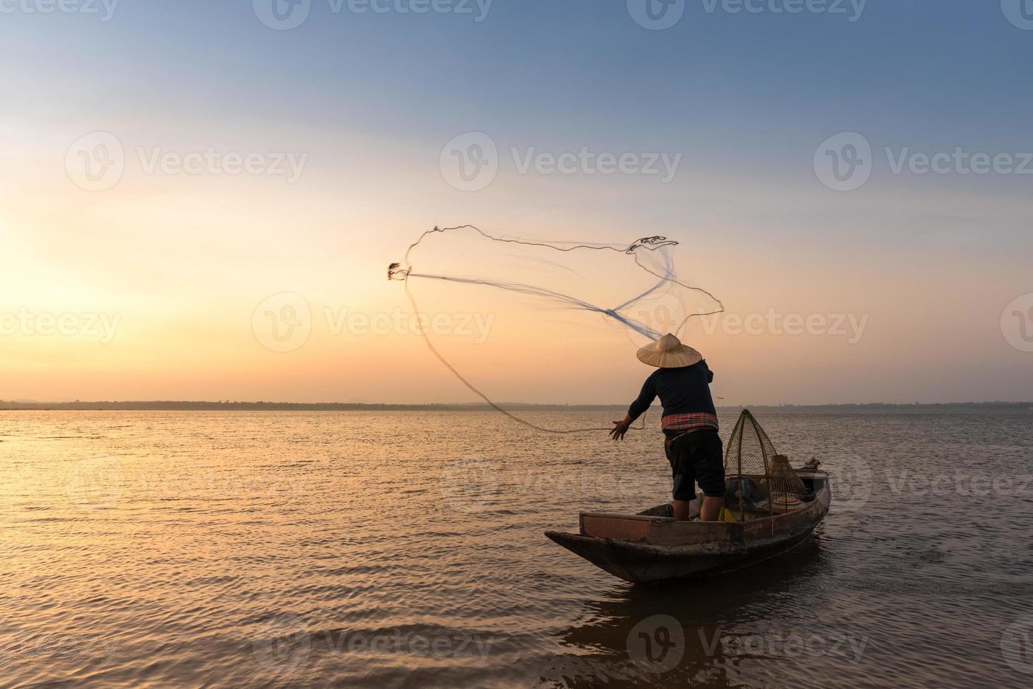 pescatore asiatico con la sua barca di legno nel fiume naturale al mattino presto prima dell'alba foto