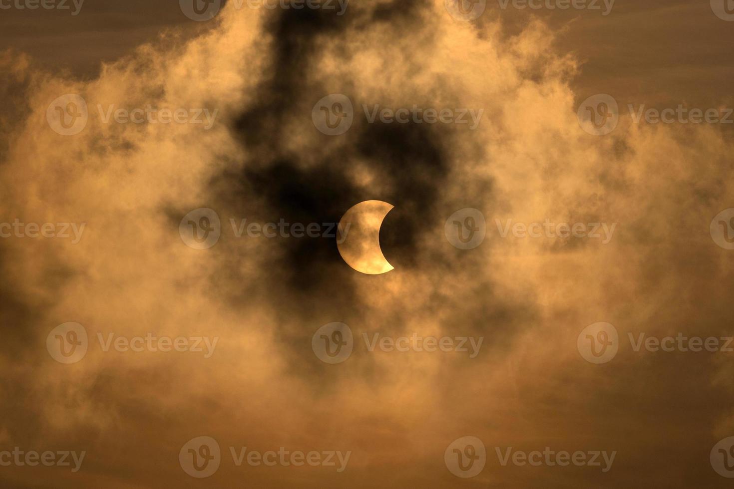 la luna che copre il sole in un'eclissi parziale con nuvole drammatiche. background scientifico, fenomeno astronomico. foto