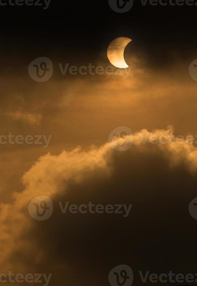 la luna che copre il sole in un'eclissi parziale con nuvole drammatiche. background scientifico, fenomeno astronomico foto