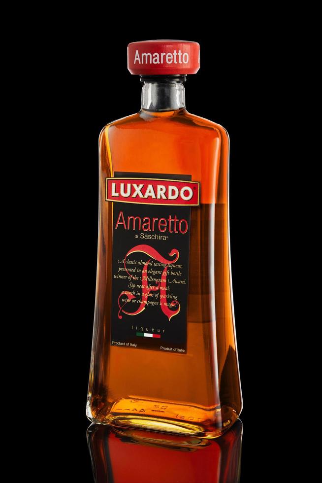 liquore italiano amaretto su sfondo nero con la riflessione. foto