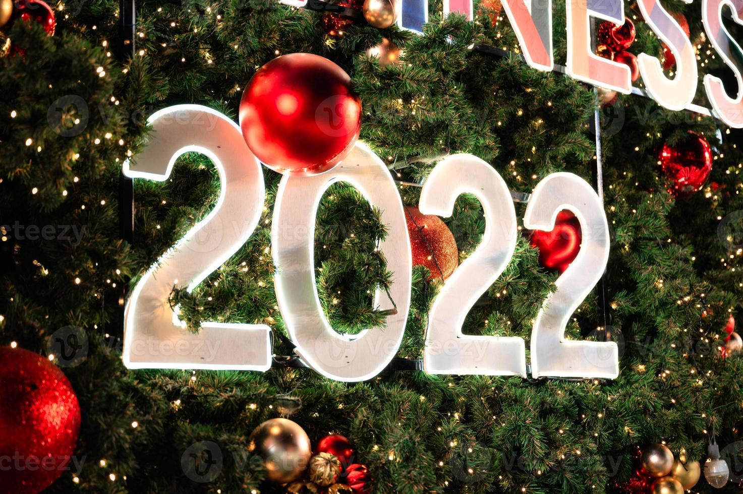 felice anno nuovo 2022 incandescente su albero di natale e palline ornamentali foto