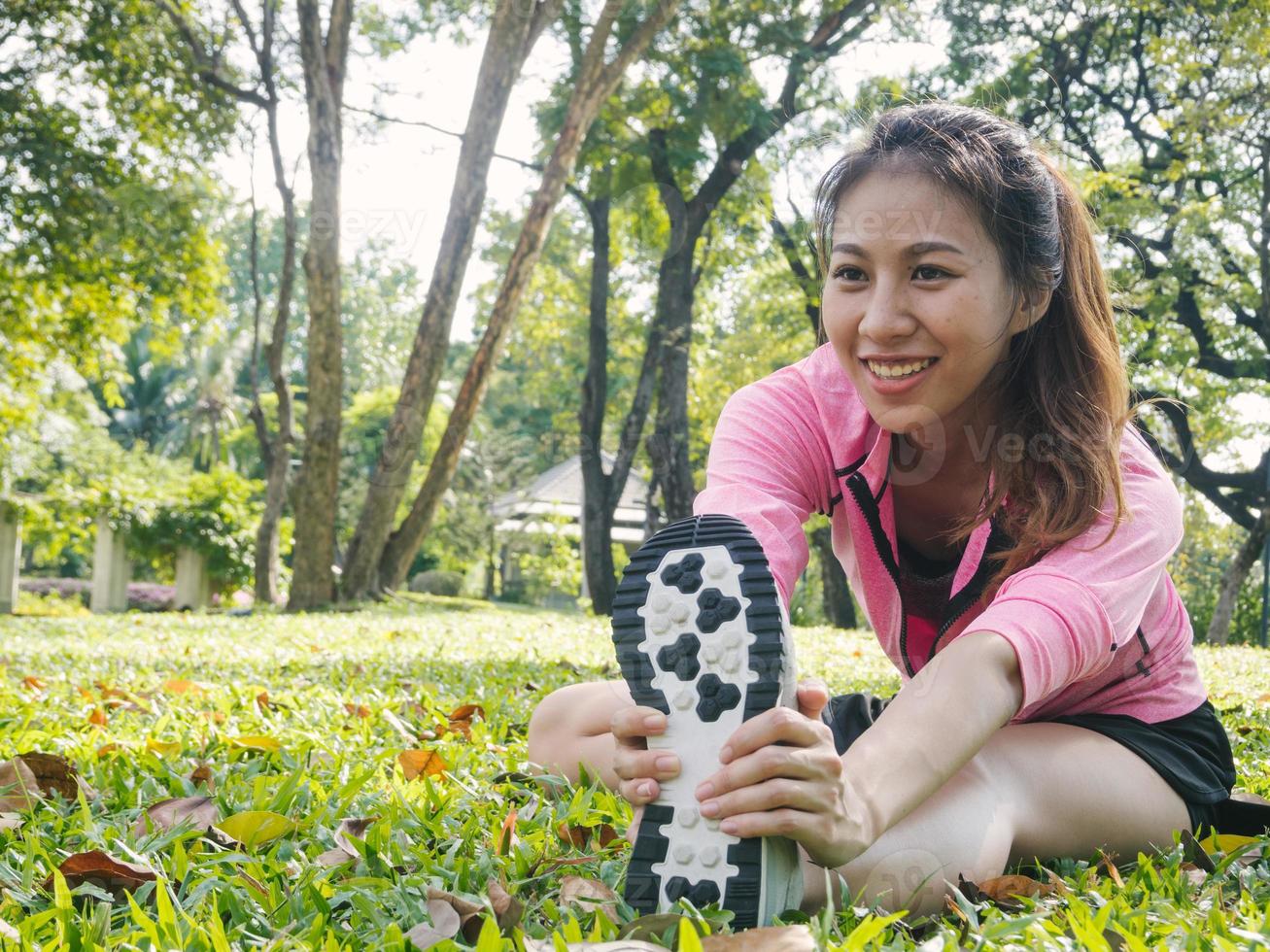 giovane donna asiatica in buona salute che si esercita al parco. giovane donna in forma che fa allenamento di formazione al mattino. giovane donna asiatica felice che si estende al parco dopo un allenamento in esecuzione. concetto di esercizio all'aperto. foto