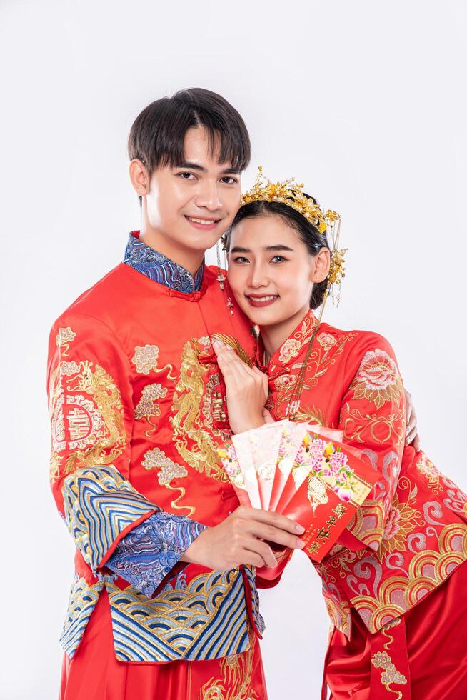 l'uomo e la donna indossano il cheongsam mostrando i soldi del regalo rosso dalla famiglia nel giorno tradizionale foto