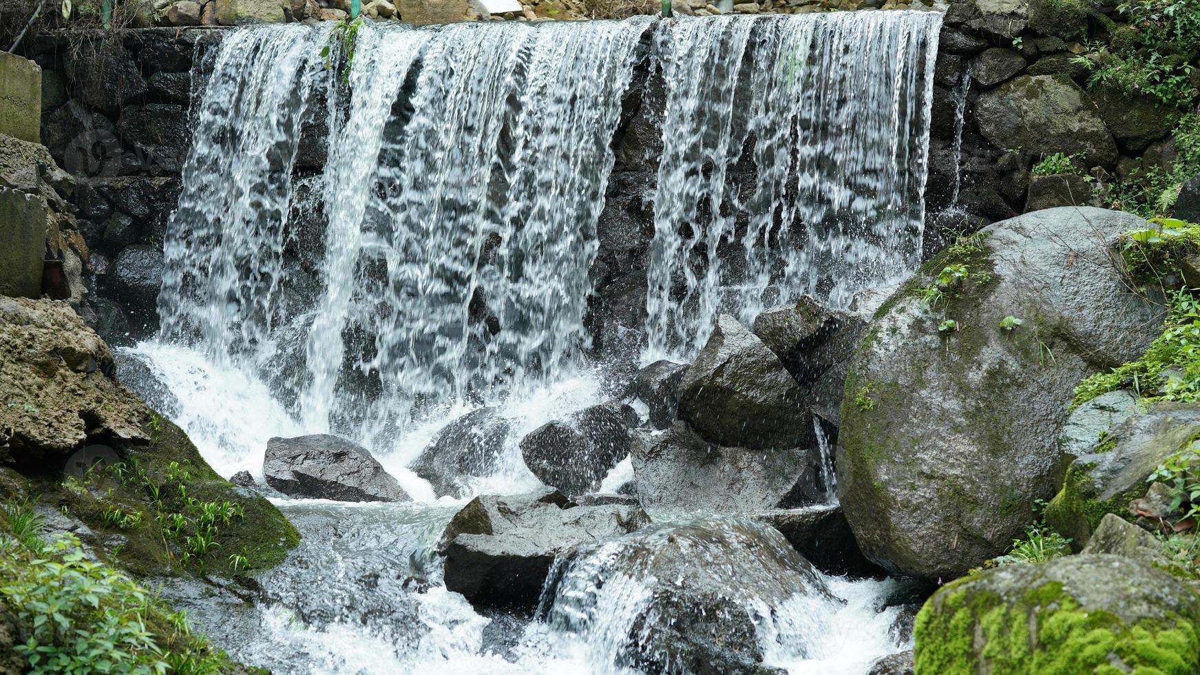 la bellissima vista sulla campagna con la cascata che scorre in montagna dopo la giornata di pioggia foto