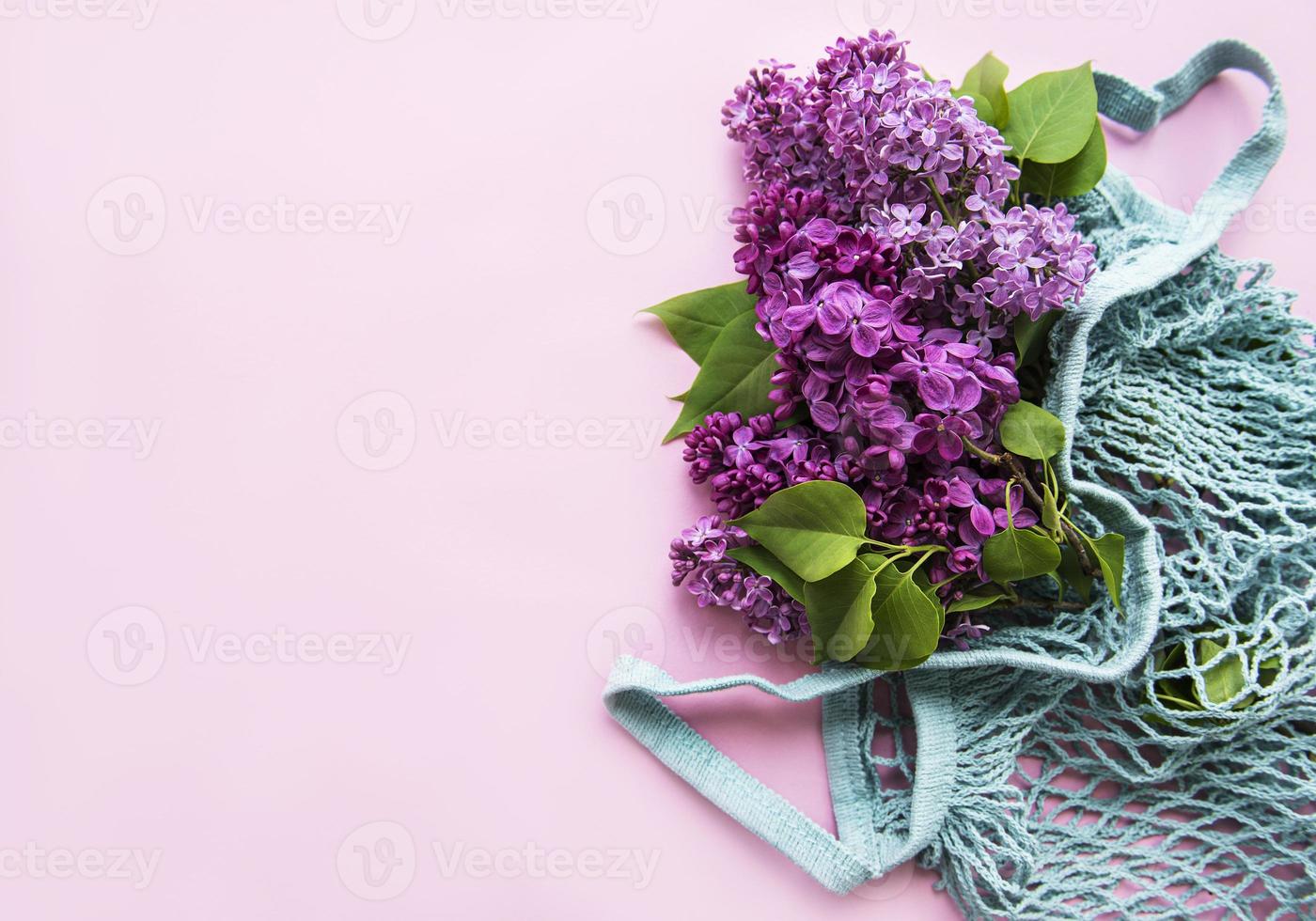 bouquet di lillà in borsa a rete eco riutilizzabile per lo shopping su sfondo rosa. concept no plastica, zero sprechi. copia spazio modello vista dall'alto per biglietto di auguri, cartolina, invito. foto