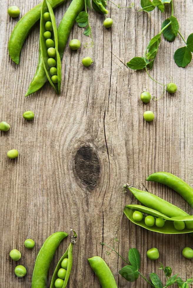 baccelli di piselli con foglie di pisello su un vecchio fondo di legno. cibo organico. foto