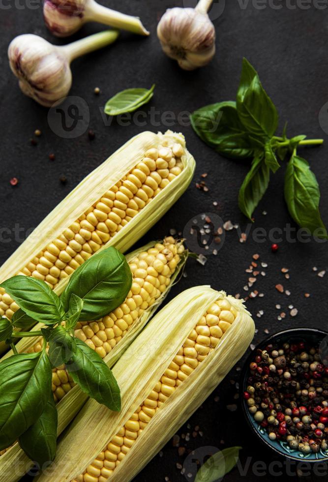 pannocchia di mais maturo su sfondo nero con spezie foto