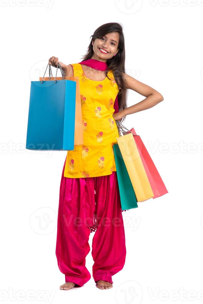 bella ragazza indiana che tiene e posa con le borse della spesa su uno sfondo bianco foto